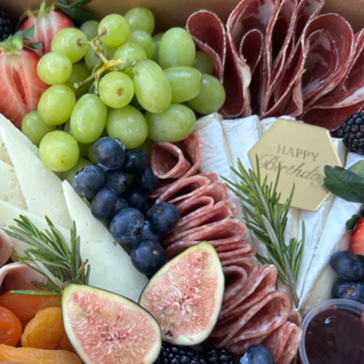 Gourmet charcuterie box with meats, cheeses, fruits, and figs