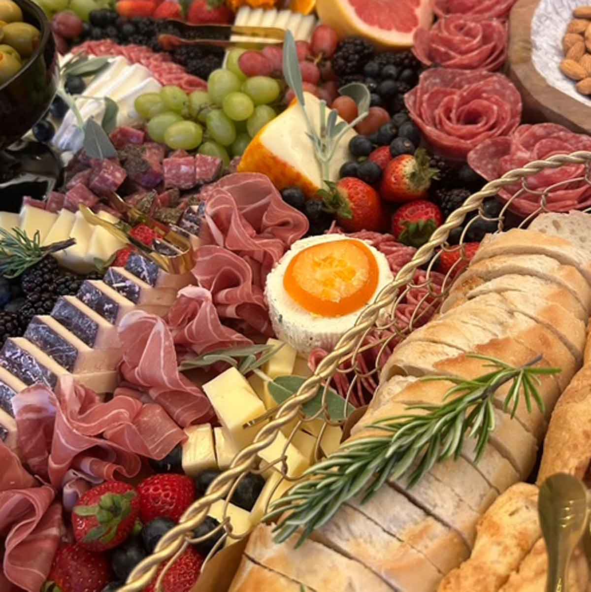 Assorted meats, cheeses, fruits, and bread on a platter.